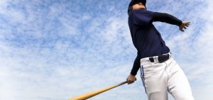 baseball player taking a swing with cloud background
